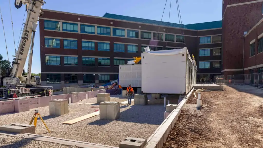  being a company leader in prefabricated and modular construction, holds modular unit being installed by crane outside a hospital